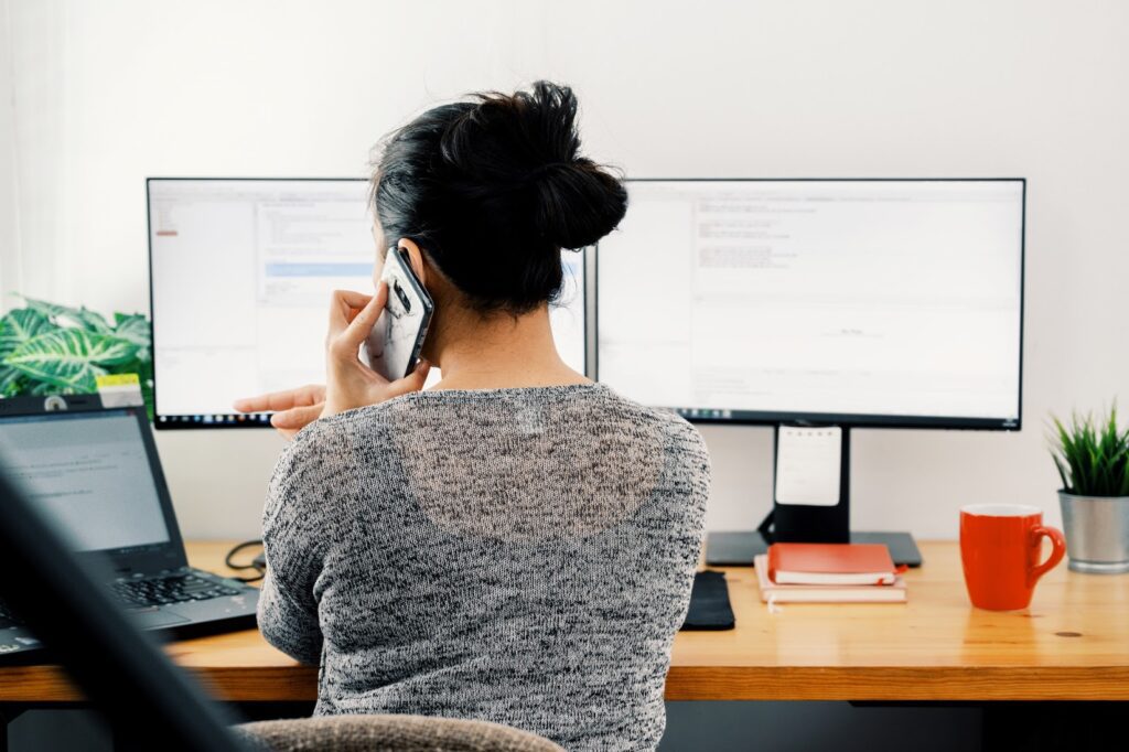 A woman sitting at her desk talking on the phone.