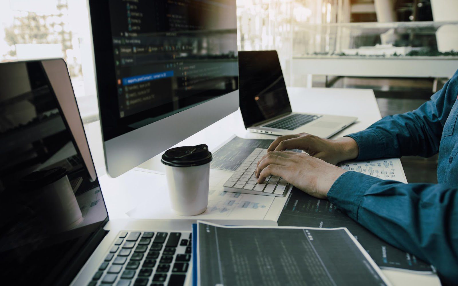 A person is typing on a laptop and drinking coffee.