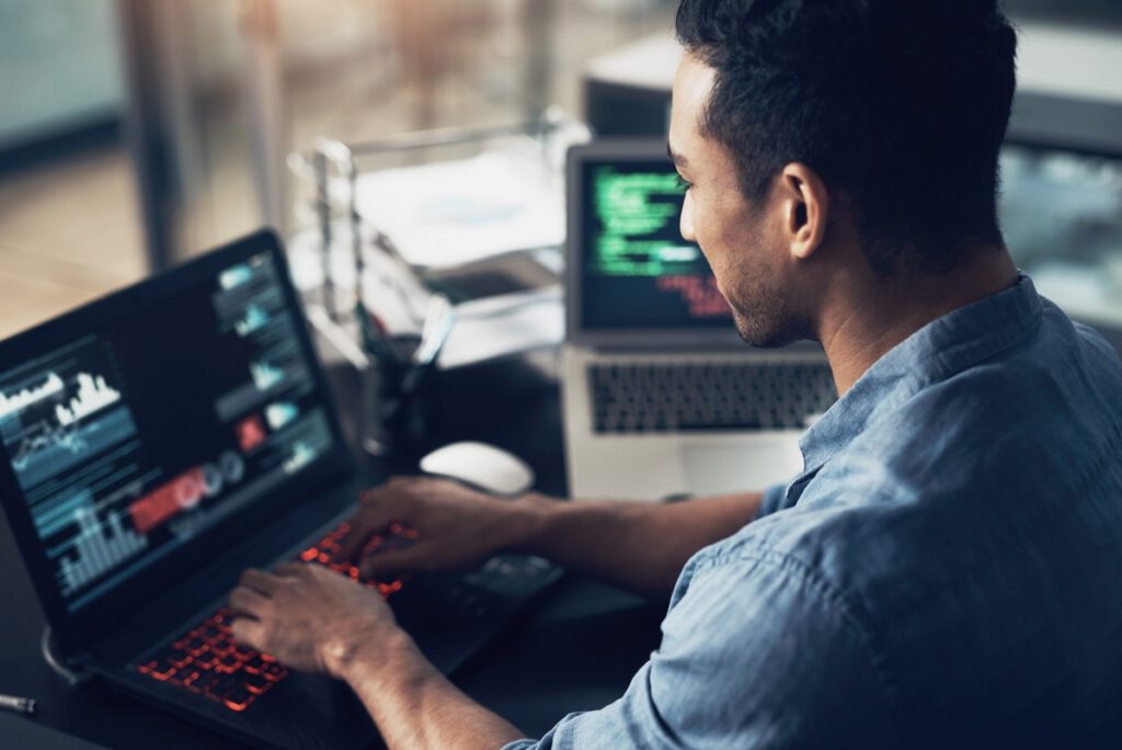 A man sitting at his computer desk typing on the keyboard.